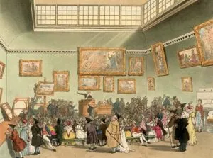 Interior de una sala de subastas donde personas miran y un subastador esta animando a los postores a pujar por objetos antiguos de arte y cuadros